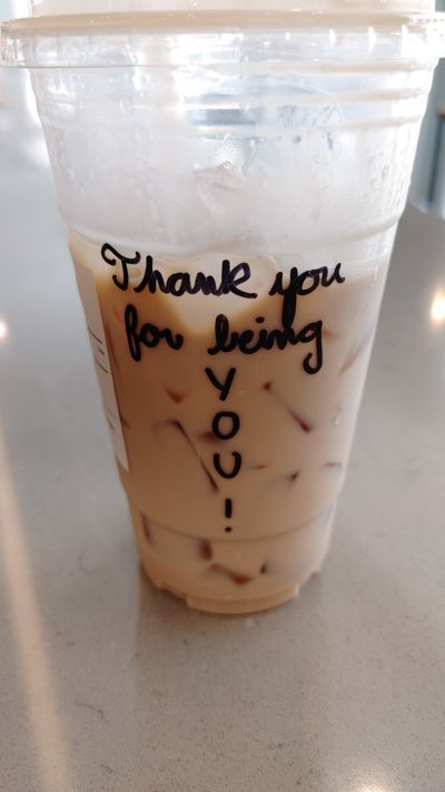 An iced late in a plastic cup with the words "Thank you for being you written on it."
