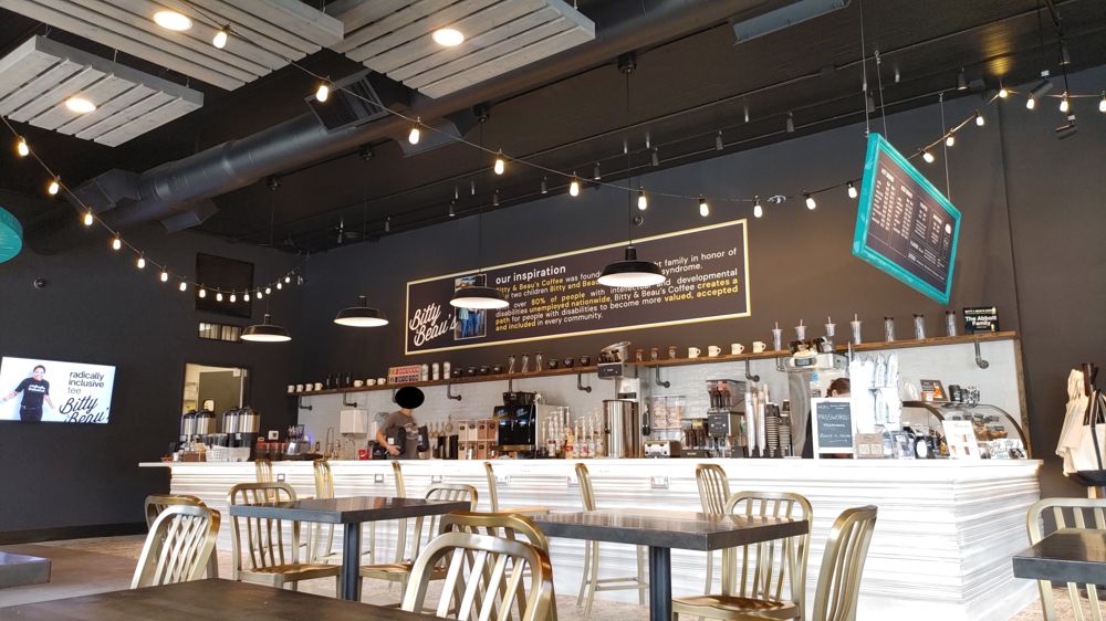 picture within the coffee shop. It shows the bar area with a sign behind it stating their values of employing people with disabilities with dignified work.