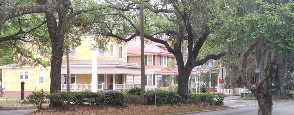 houses in Savannah, GA with wrap around porches. Beautiful Oak trees with Spanish moss are in front.